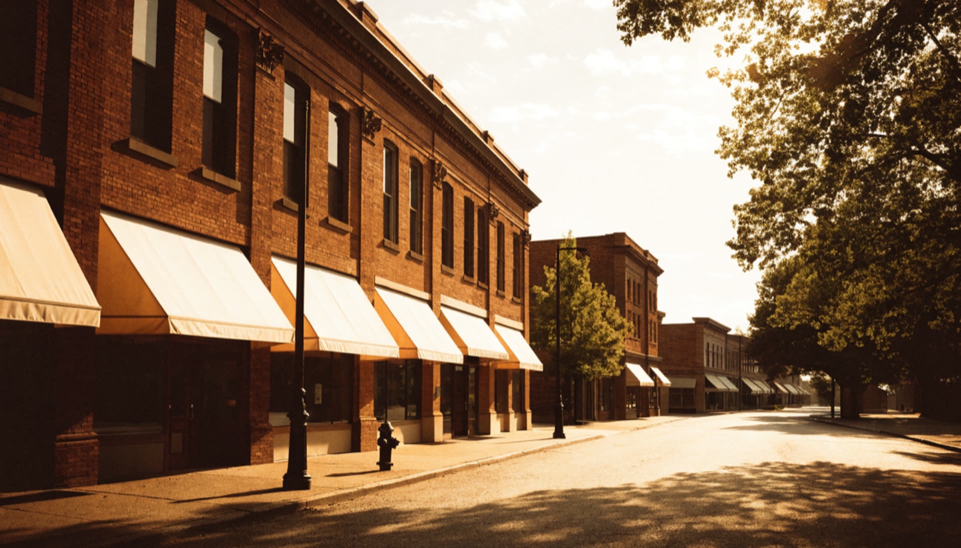 Brick storefront facades with awnings on a small-town main street in golden morning light
